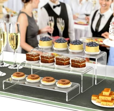 Acrylic risers with a selection of desserts, adding elegance to a catered event setup.