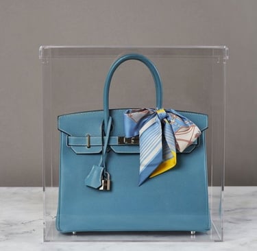 Blue luxury bag in a sleek acrylic display case.