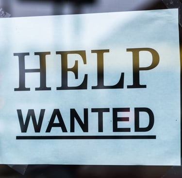 A "Help Wanted" sign taped to a store window