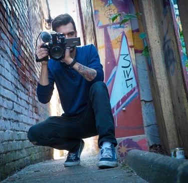 Corbin Veltum, holding a video camera in an alleyway