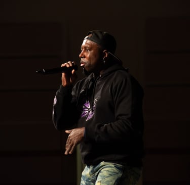 A rapper wearing a backwards baseball cap, standing on a stage at church