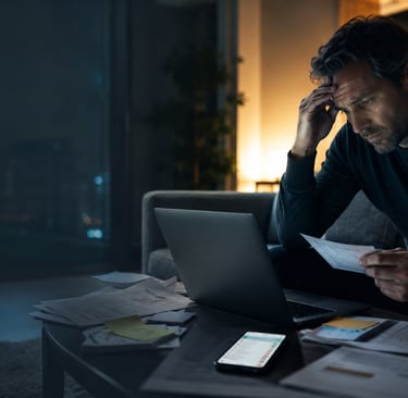 Person facing laptop with urgent notifications, documents and growing tension, symbolizing fear, risk and delayed reaction.