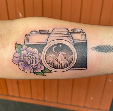 Tattoo of camera with a mountain scenery and flower