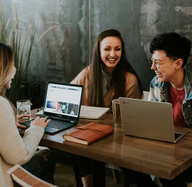 a group of people sitting at a table with laptops