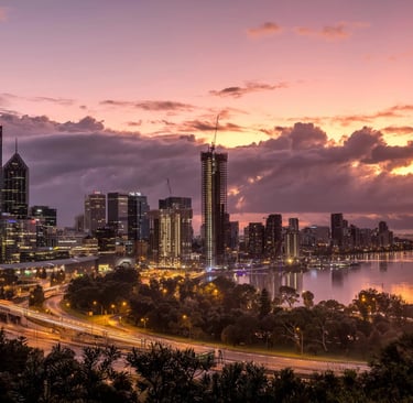 a city skyline with a river and a sunset