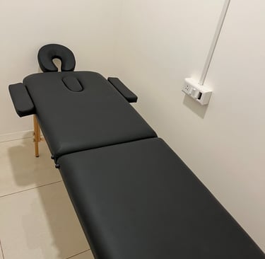 A massage table in a peaceful room with a bright white wall, designed for comfort and relaxation during massage therapy