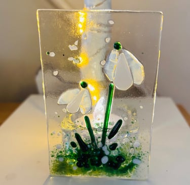 a fused glass tea light holder with a flower inside of it