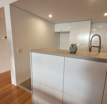 Modern white kitchen interior featuring a minimalist island, white cabinetry, and a decorative owl figurine.