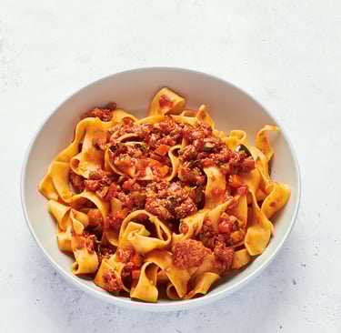 a bowl of pasta with vegan protein mince meat and vegetables