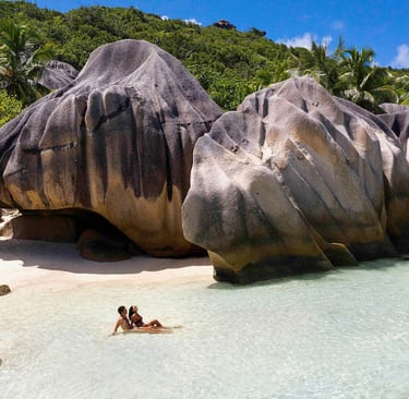 Guests relaxing on white sand beach next to giant granite boulders (photo courtesy of Expedia)