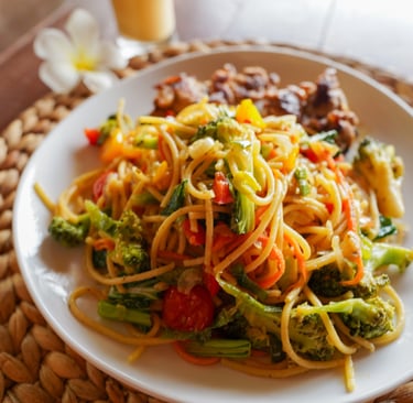 Plate of fresh vegetable pasta with broccoli, tomatoes, and Indonesian spices at Toska Mentawai
