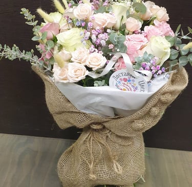 Hand-tied pastel floral arrangement in rustic burlap wrap