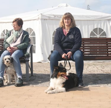 Kurze Pause. Zwei Kunden sitzen auf einer Bank am Südstrand mit ihren Hunden