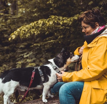 Marion Lindhof im Wald mit Pensionshund Trapper., der Nähe sucht.