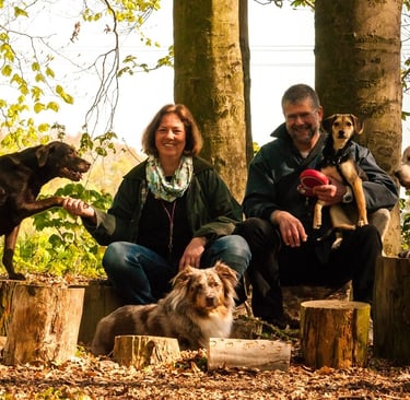 Marion und Martin Lindhof relaxed im Wald mit vier Hunden.