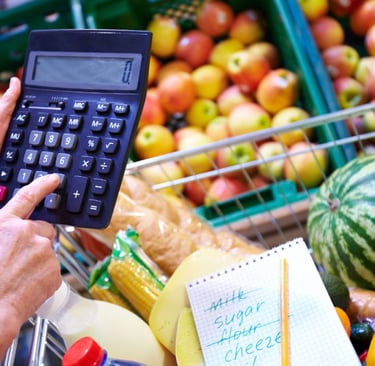 imagem mostra uma pessoa usando uma calculadora para somar o preços dos alimentos que estão caros