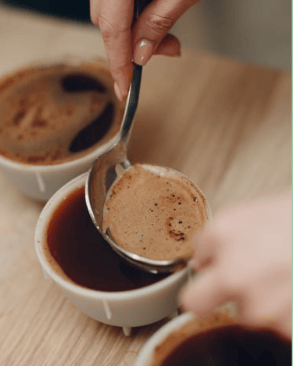 a person is spooning out of a cup of coffee