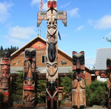 Hand-carved Alaskan totem poles standing outside the Herring Cove Rainforest Sanctuary in Ketchikan.