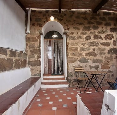 Entrance of a dammuso in Rekhale with stone arch, beaded curtain and tiled patio