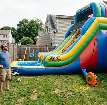 large inflatable slide in a small backyard. The slide is too big for the yard and parents are standi