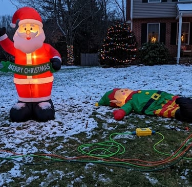 Large outdoor holiday display showing multiple inflatables,and one failed inflatable beside a proper