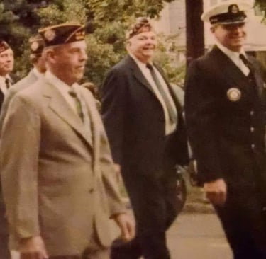 a group of veterans in suits and hats walking down a street