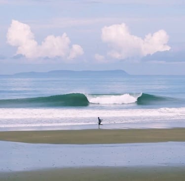Surfer running on the beach with a perfect wave and an island on the back on a sunny day