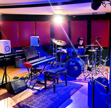 a recording studio with a e-piano, drums, and Keys