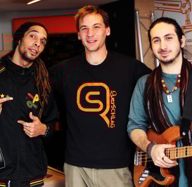 three men standing next to each other prducing songs, one is holding a guitar