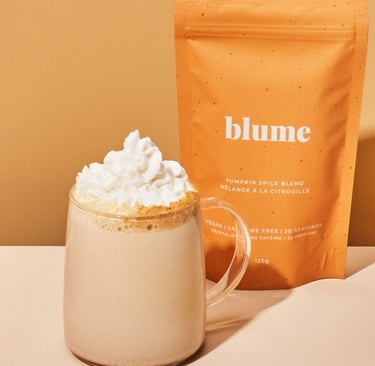 A cup of pumpkin spice latte with whip cream on top along with the orange bag of pumpkin spice latte mix beside it.