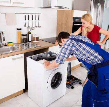a man and woman working on a washing machine