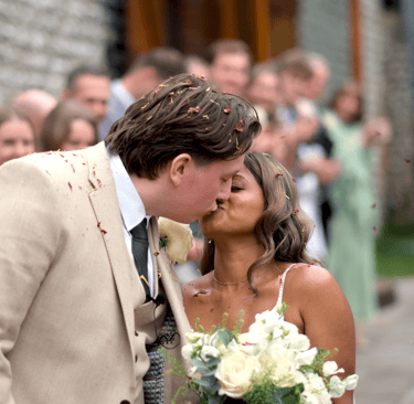 A bridge and groom kissing with confetti being thrown