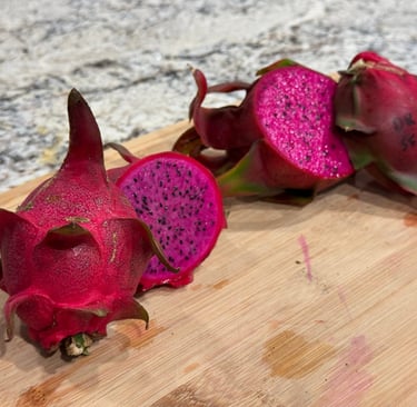 Dragon Fruit, whole and cut open, on a wooden cutting board