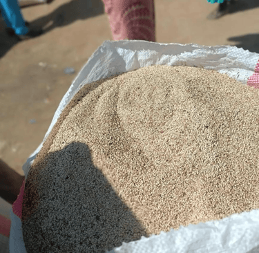 A large white sack filled with organic sesame seeds at an outdoor agricultural market.