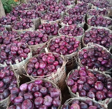 Woven baskets filled with fresh red onions at a vibrant local produce market.