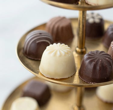 Surtido de trufas de chocolate gourmet y pralinés de chocolate blanco exhibidos en un puesto.
