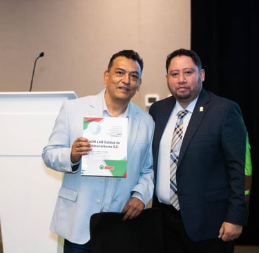 Two professional men holding an ACM LAB Calidad de Hidrocarburos certificate at an AMPES event.