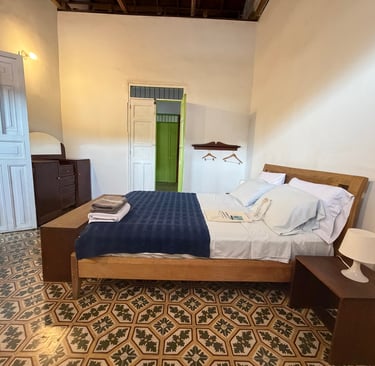 Rustic bedroom with patterned tile floors, wooden bed frame, and vintage white doors.