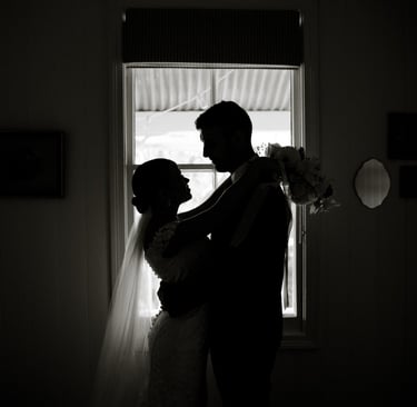 a bride and groom standing in front of a window
