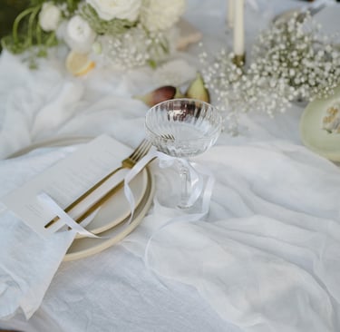 a table setting with a white table cloth and a glassware