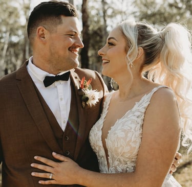 a bride and groom standing in a wooded area