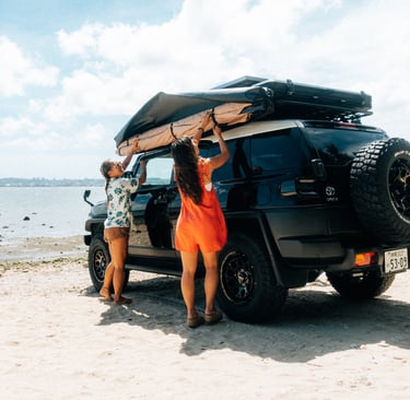 Two women setting up an awning attached to their Toyota FJ Cruiser on the beach in Okinawa. | Evertrail Okinawa