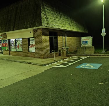 Accessible parking spot with blue ADA symbol and hatched access zone at night.