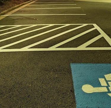 Hatched access aisle and ADA blue marking with clean striping near a sidewalk at night.