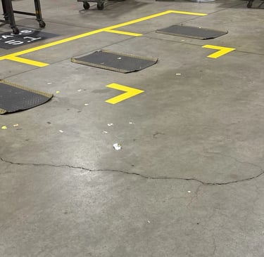 Precision yellow safety striping and directional chevrons painted on a warehouse concrete floor