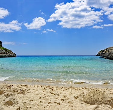 Cala Anguila beach in Mallorca with a blue sky and some clouds