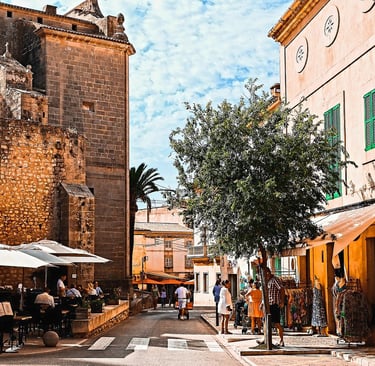 Town in Mallorca with people walking and sitting near an old building