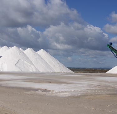 Large white salt piles at a salt production facility in Ses Salines Mallorca under a cloudy sky