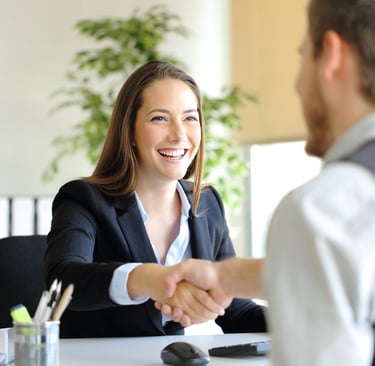 Smiling interviewer shaking hands with candidate, symbolizing a successful interview.