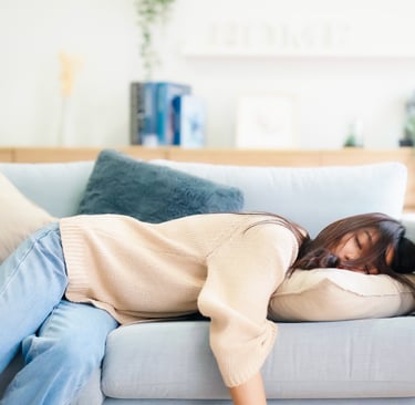 Person napping on a couch with their head on a pillow.